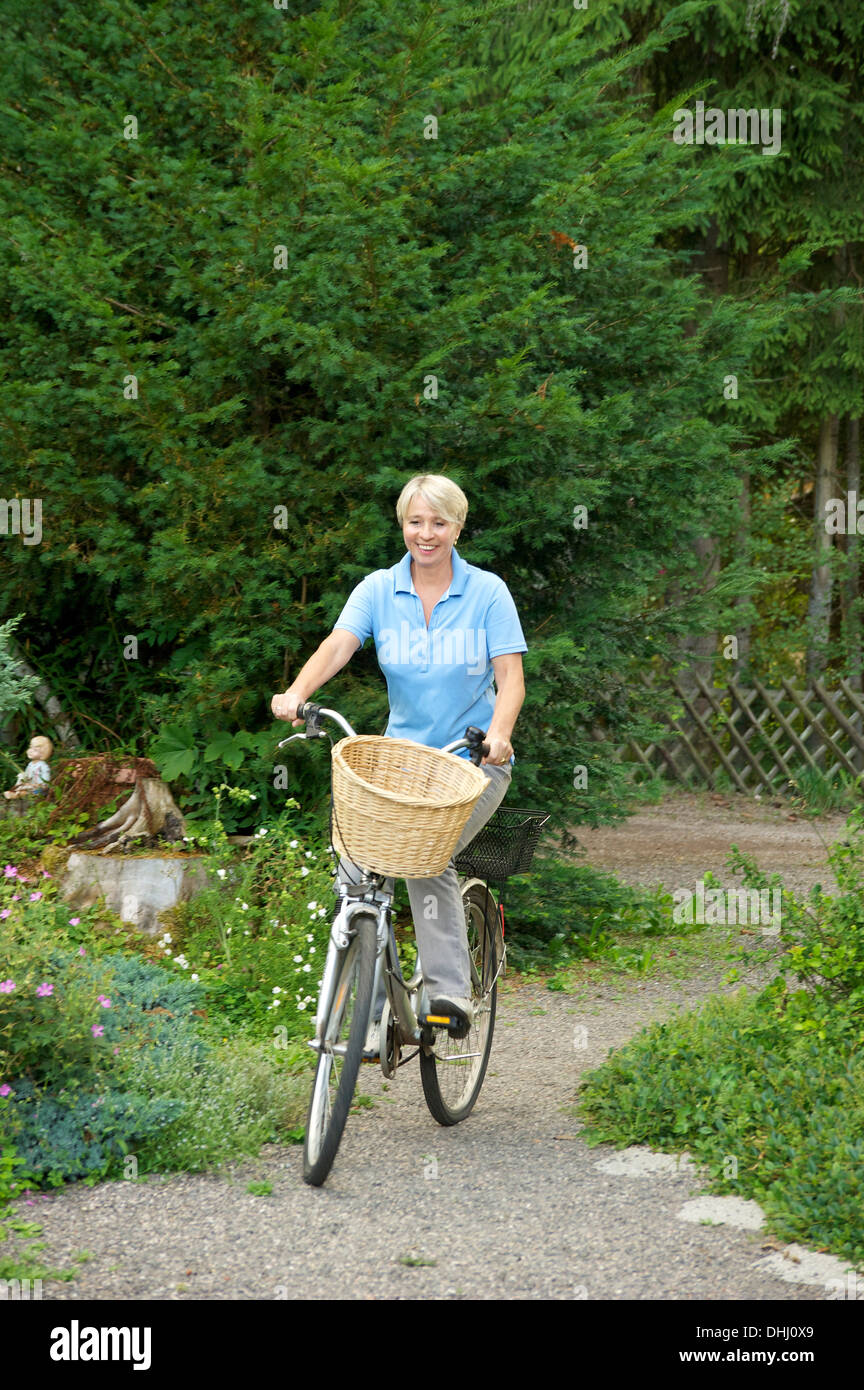 Mujer senior de equitación en el parque de bicicletas Foto de stock