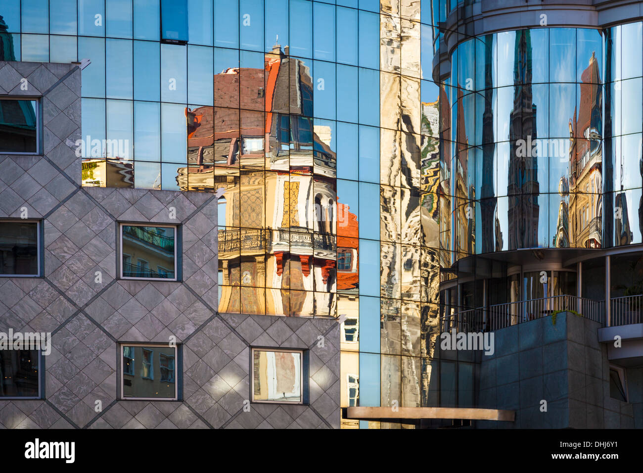 Edificio de arquitectura abstracta con el reflejo del cielo y antigua iglesia en Viena, Austria. Foto de stock