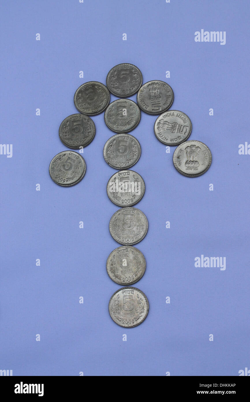 Monedas dispuestos en forma de flecha ascendente mostrando crecimiento en el tipo de cambio o crecimiento económico Foto de stock