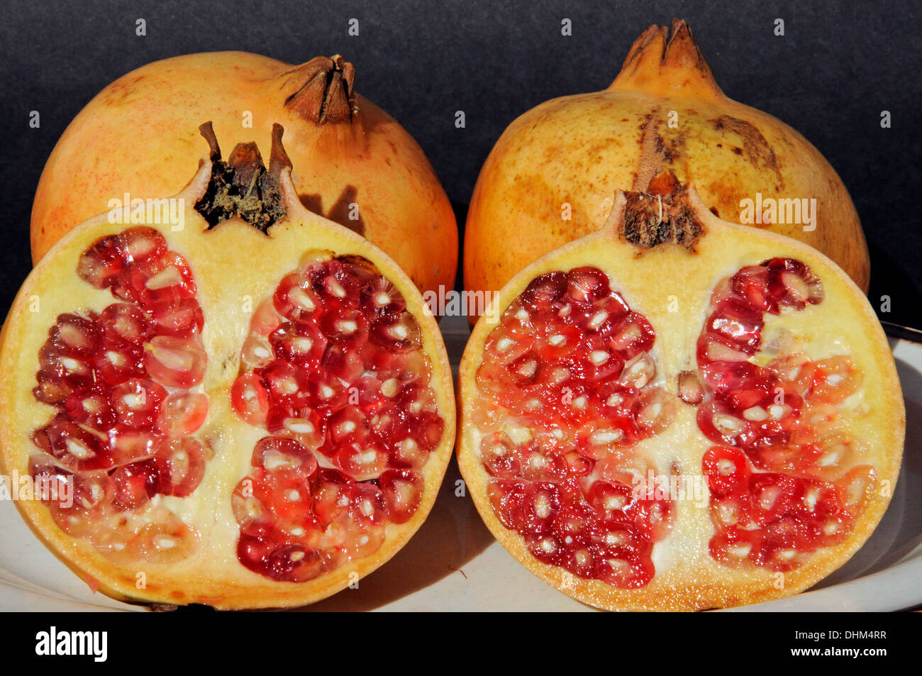 Las granadas cortadas en la mitad mostrando fruta roja en su interior. Foto de stock