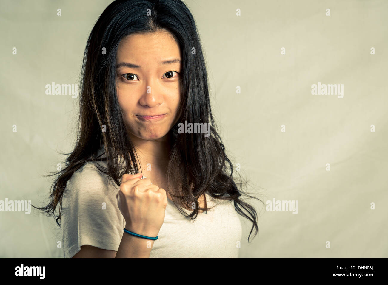 Mujer joven apretamiento su puño para el aliento, con tono de moda y antecedentes Foto de stock
