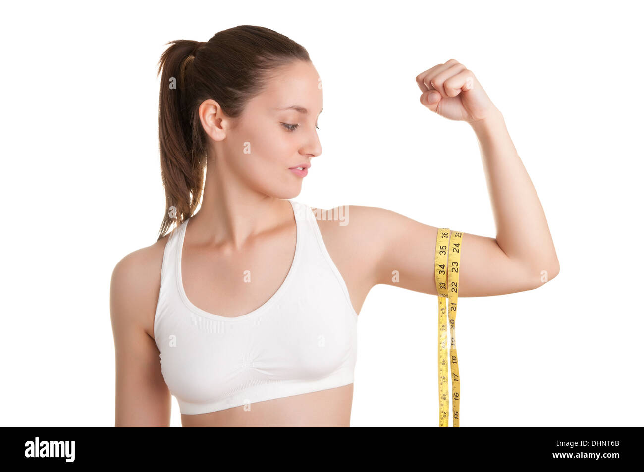 Mujer poderosa midiendo sus bíceps con una cinta de medición amarilla Foto de stock