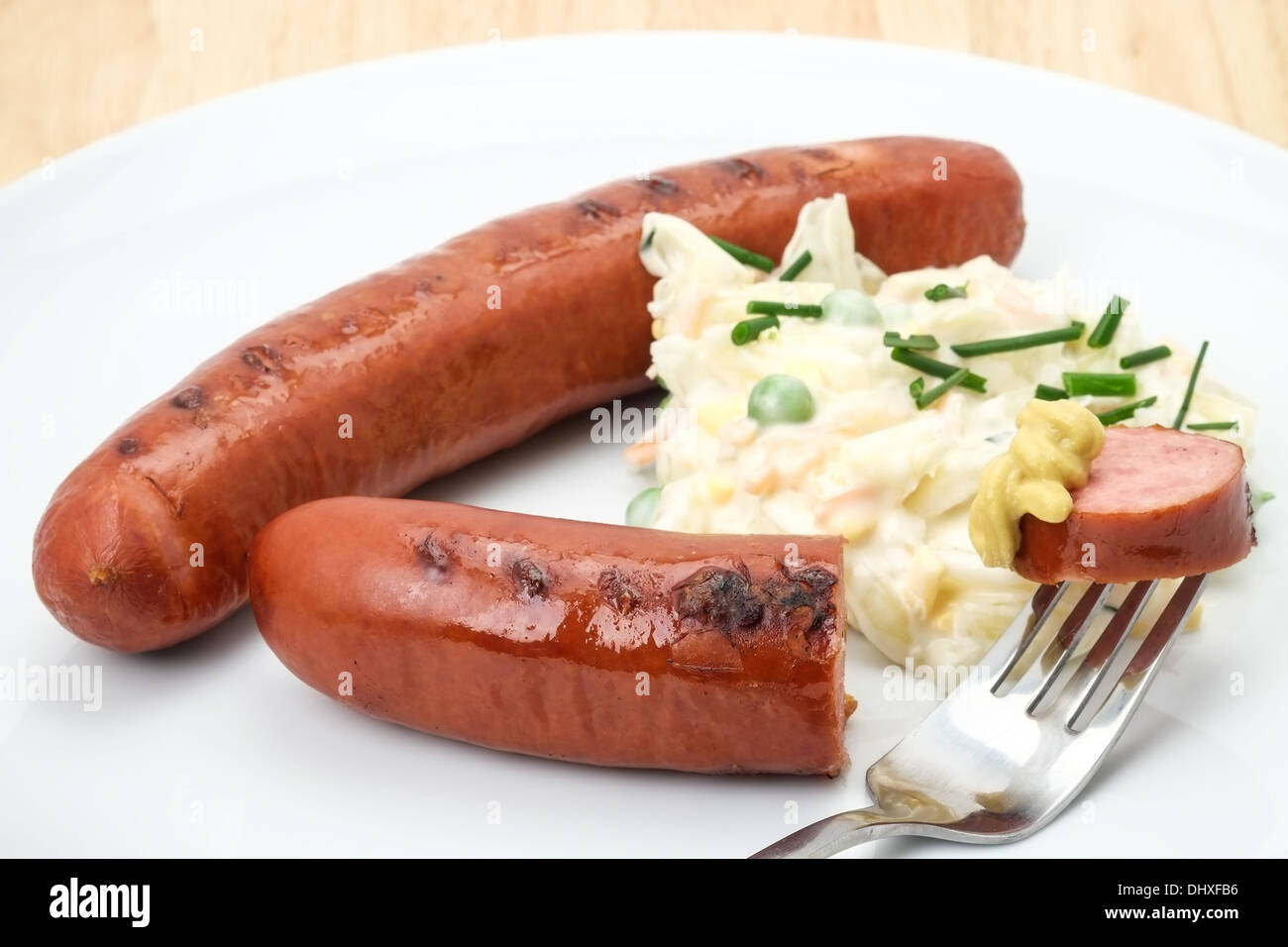 Close-up de un listo para comer salchichas Bratwurst alemana servido con coleslaw y mostaza. Foto de stock