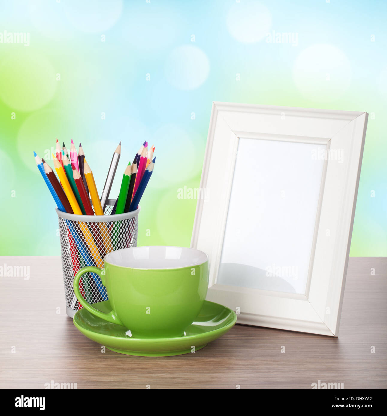 Marco de foto, taza de café y lápices de colores sobre la mesa de madera a lo largo de día soleado bokeh de fondo Foto de stock