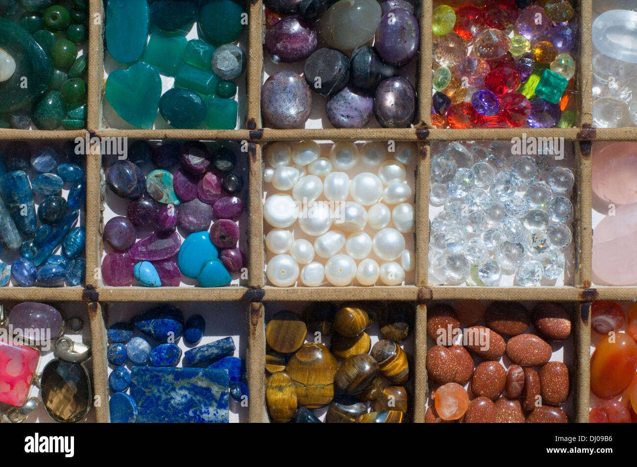 Piedras Semi Preciosas para la venta en sus cajas pequeñas. Ojo de tigre, lapiz, perlas, cristal de cuarzo ahumado Foto de stock