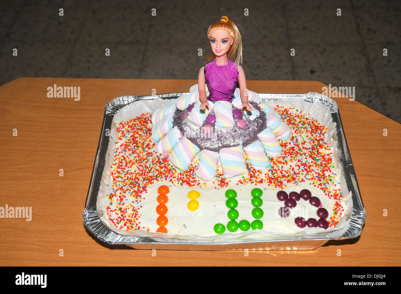 Muñeca barbie sosteniendo un pastel de cumpleaños con velas y