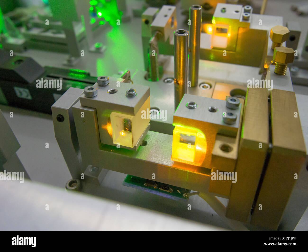 Fragmento del complicado sistema láser de laboratorio con color amarillo brillante luz generada dentro de cristales Foto de stock
