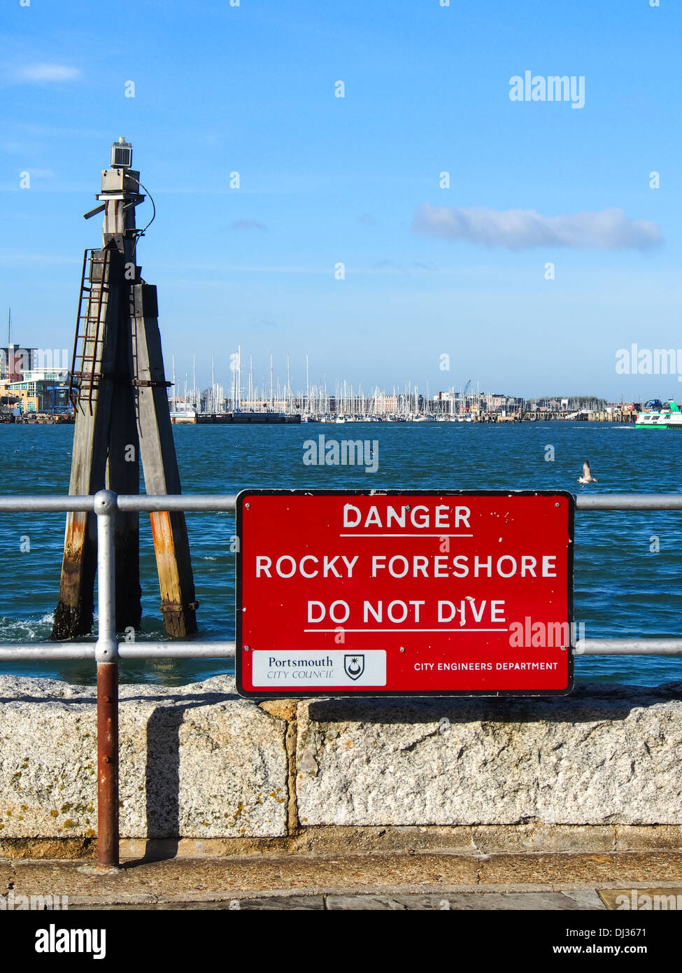 Un signo leyendo 'Danger, Rocky foreshore no bucean' en el puerto de Portsmouth, Inglaterra Foto de stock