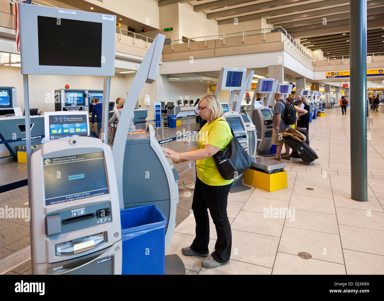 Calgary mujer mediante comprobación automática en máquinas hall de salidas del aeropuerto del aeropuerto internacional de Calgary, Alberta, Canadá Foto de stock
