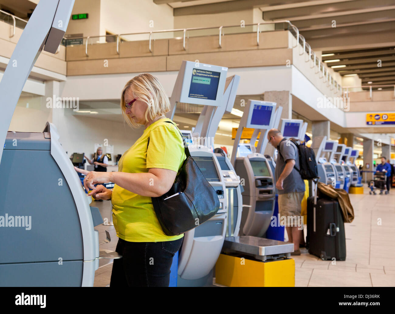 Aeropuerto internacional de Calgary mujer mediante comprobación automática en máquinas de salidas del aeropuerto de Calgary, Alberta, Canadá Foto de stock