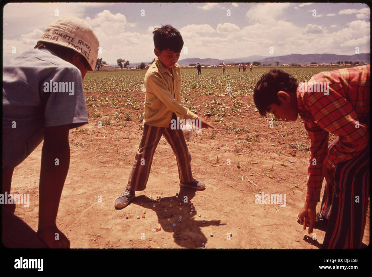 Los hijos de los trabajadores migrantes juegan canicas mientras sus padres trabajan en los campos. Porque sus familias debe constantemente . 859 Foto de stock