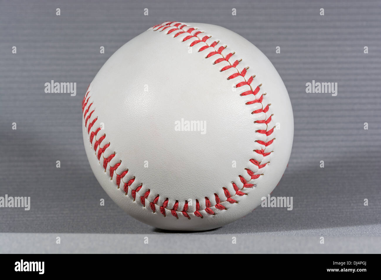 Bola de béisbol sobre fondo gris, disparo horizontal y enfoque con poca iluminación creativa Foto de stock