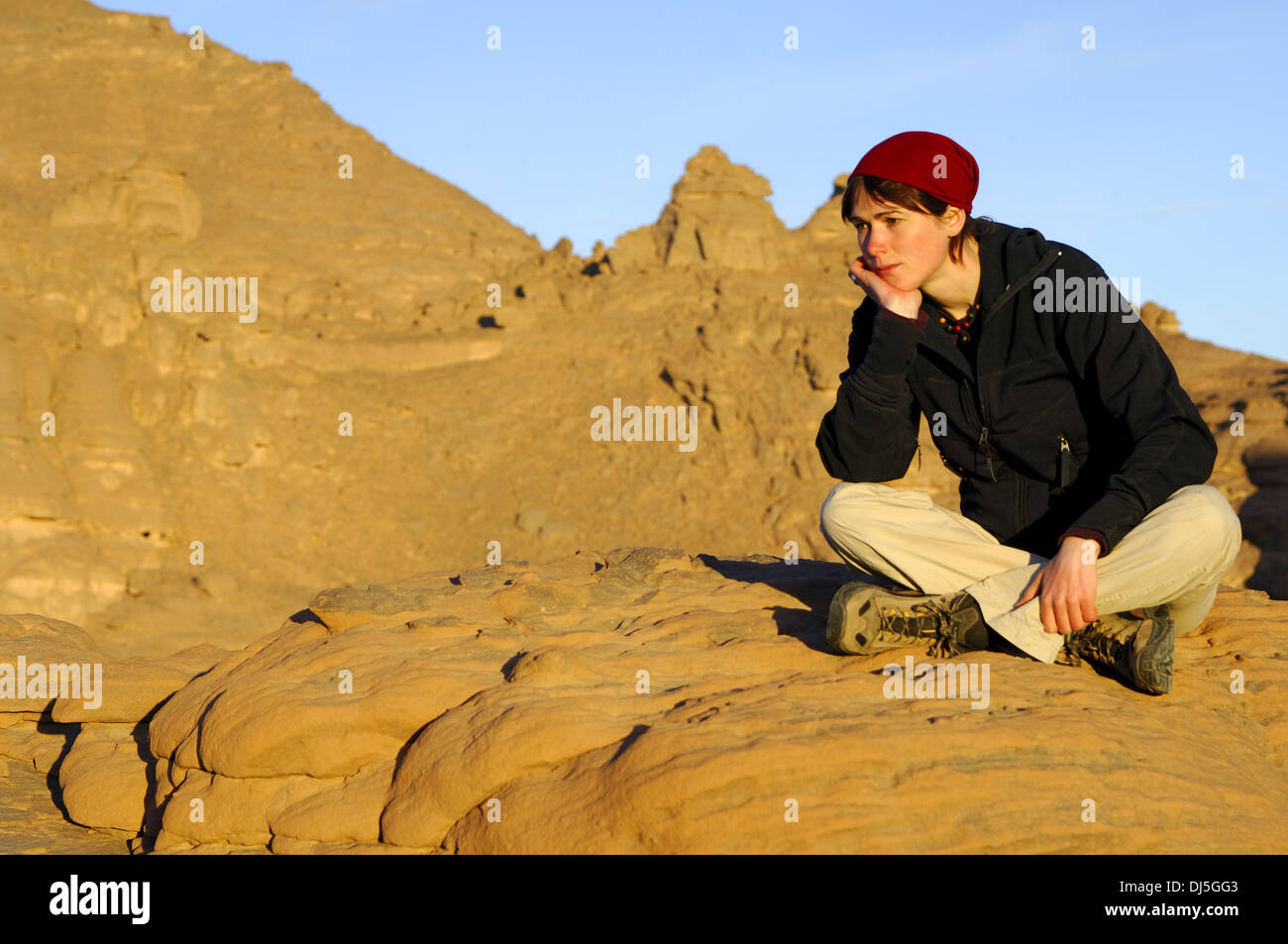 Mujer joven sentada sobre una roca estéril Foto de stock