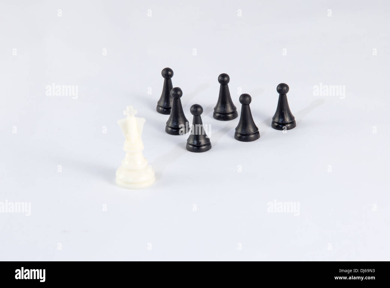 Rey blanco de ajedrez con peones negros que simbolizan el liderazgo empresarial y la diferencia Foto de stock