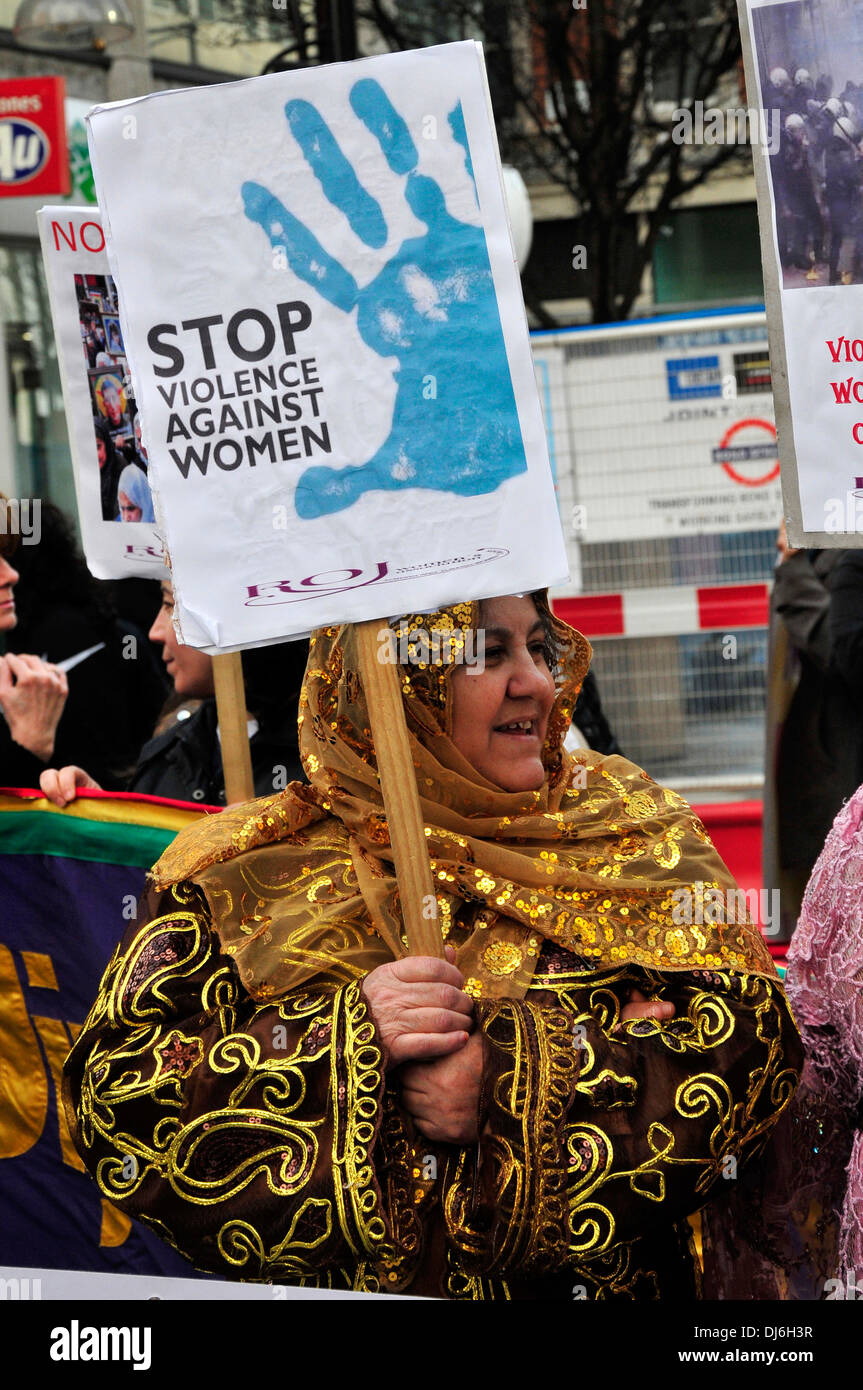 Una mujer vistiendo ropas tradicionales y un pañuelo, sosteniendo una pancarta 'No más violencia contra las mujeres", Londres, Reino Unido. Foto de stock