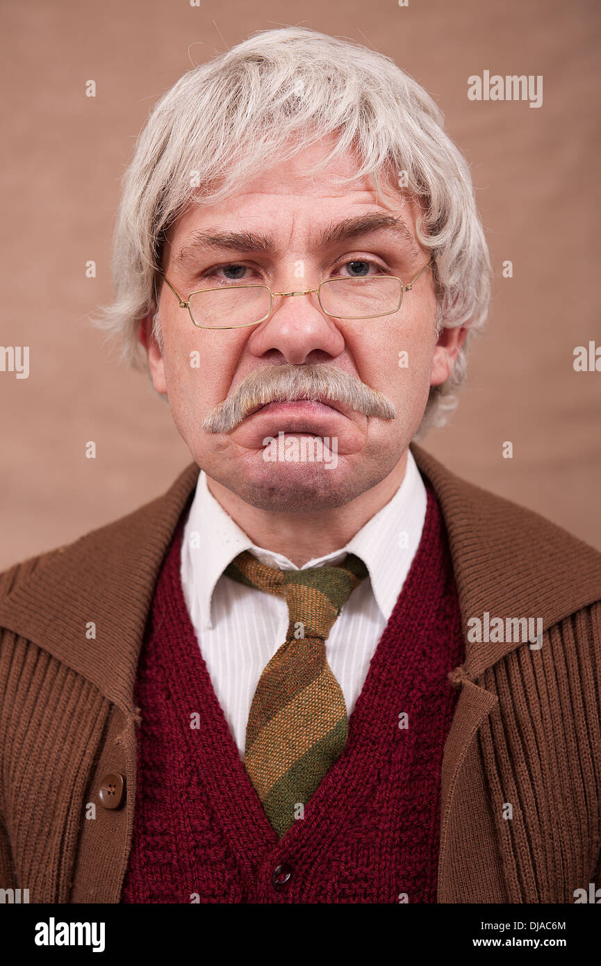 Retrato de un hombre de pelo gris gruñones contra un fondo marrón. Foto de stock