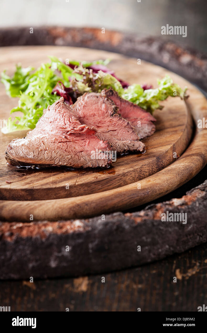 Carne asada en placa de corte con lechuga Foto de stock