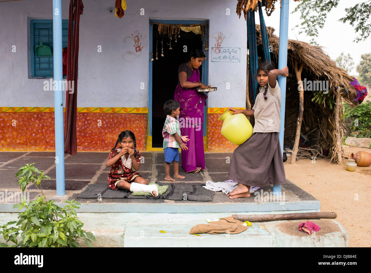 Niña india con pierna rota y familiares fuera de su aldea india home. En Andhra Pradesh, India Foto de stock
