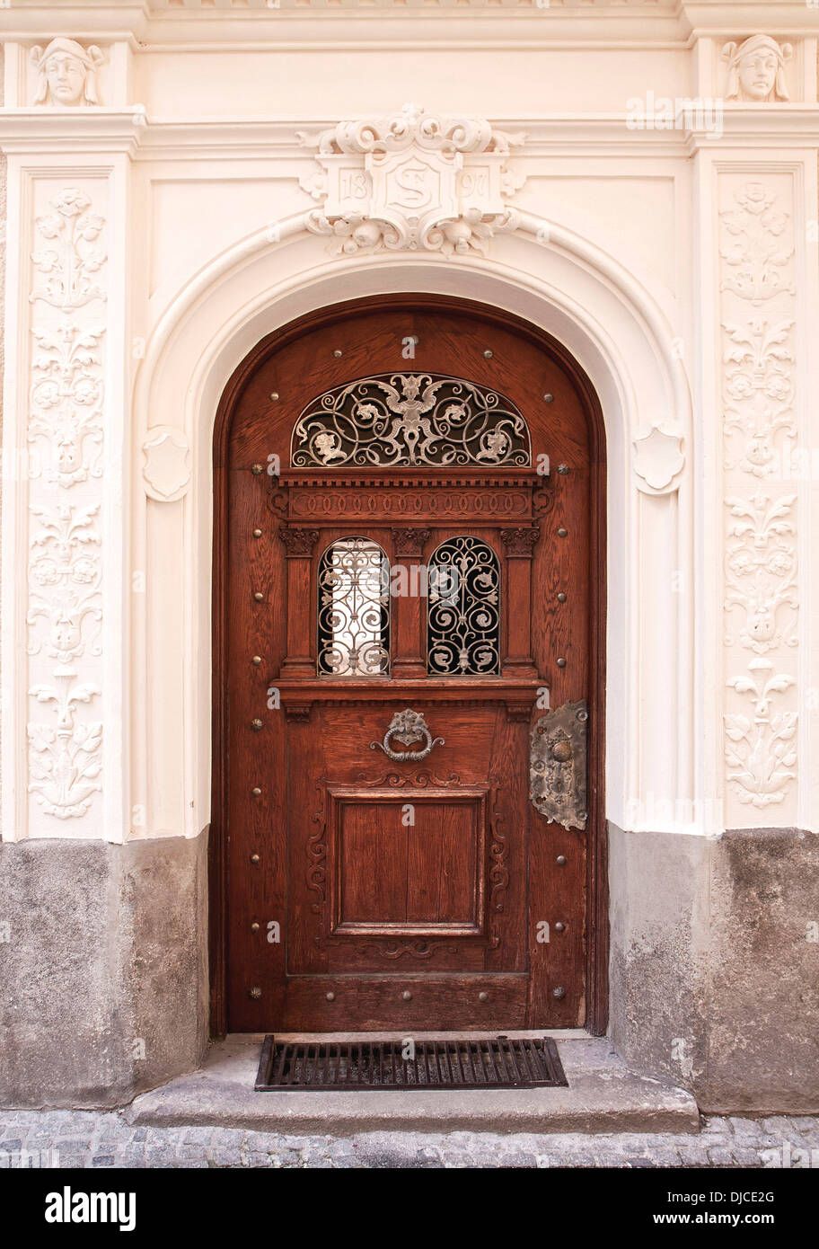 Elegante puerta de madera con empuñadura de bronce y decoraciones  elaboradas, enmarcadas por columnas de estuco y arquitrabe Fotografía de  stock - Alamy