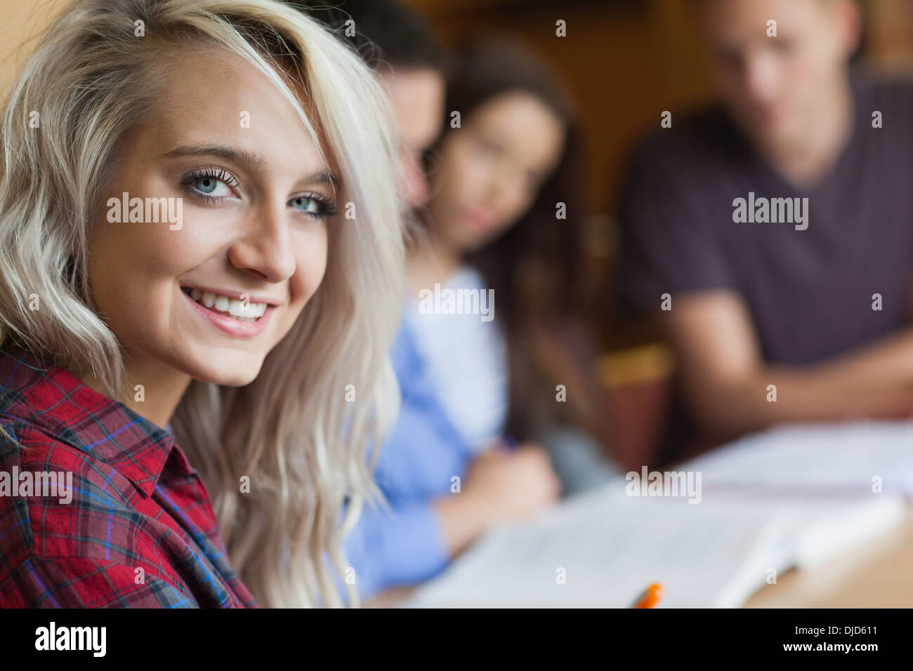 Rubia sonriente estudiante con otros estudiantes Foto de stock