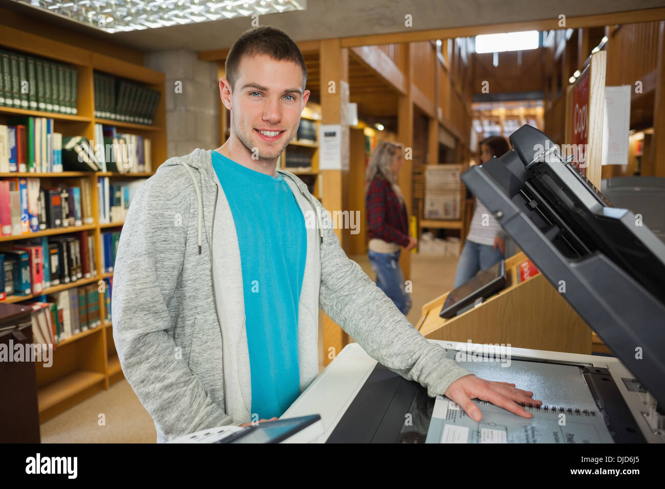 Feliz guapo estudiante usando una fotocopiadora Foto de stock