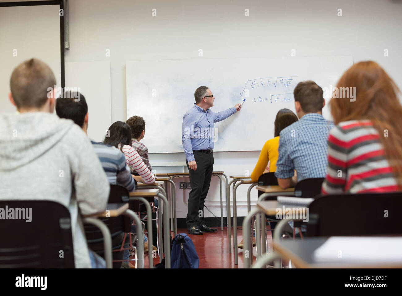 Estudiantes escuchando al profesor explicar la fórmula en la parte superior de la clase Foto de stock