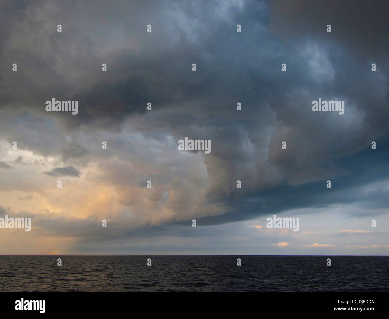 Un barrido de nubes tormentosas buscando formas un tiempo en frente del océano. Foto de stock