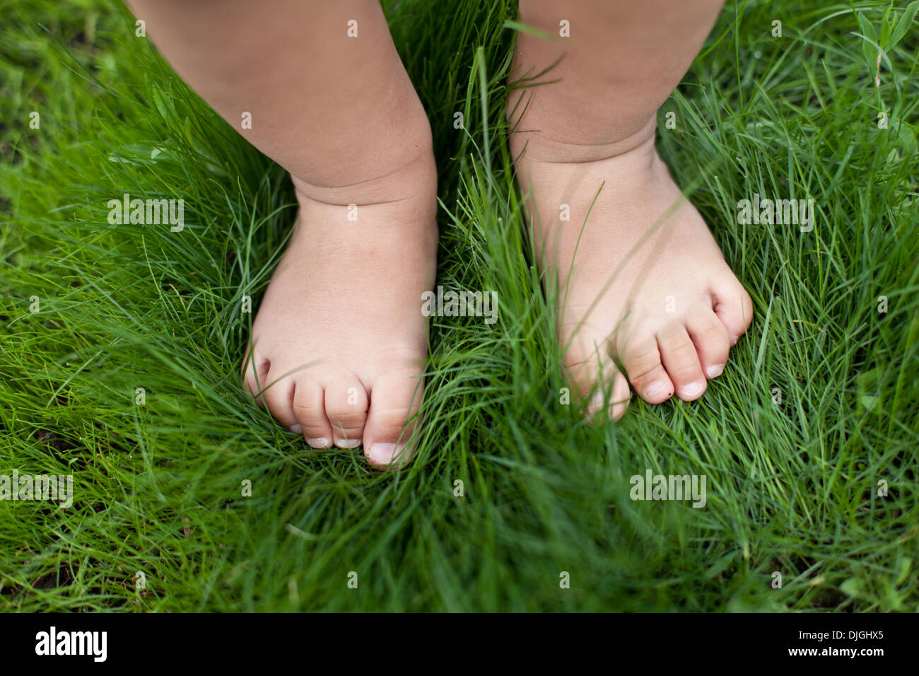 Bebé pequeño pies sobre la hierba verde. Foto de stock