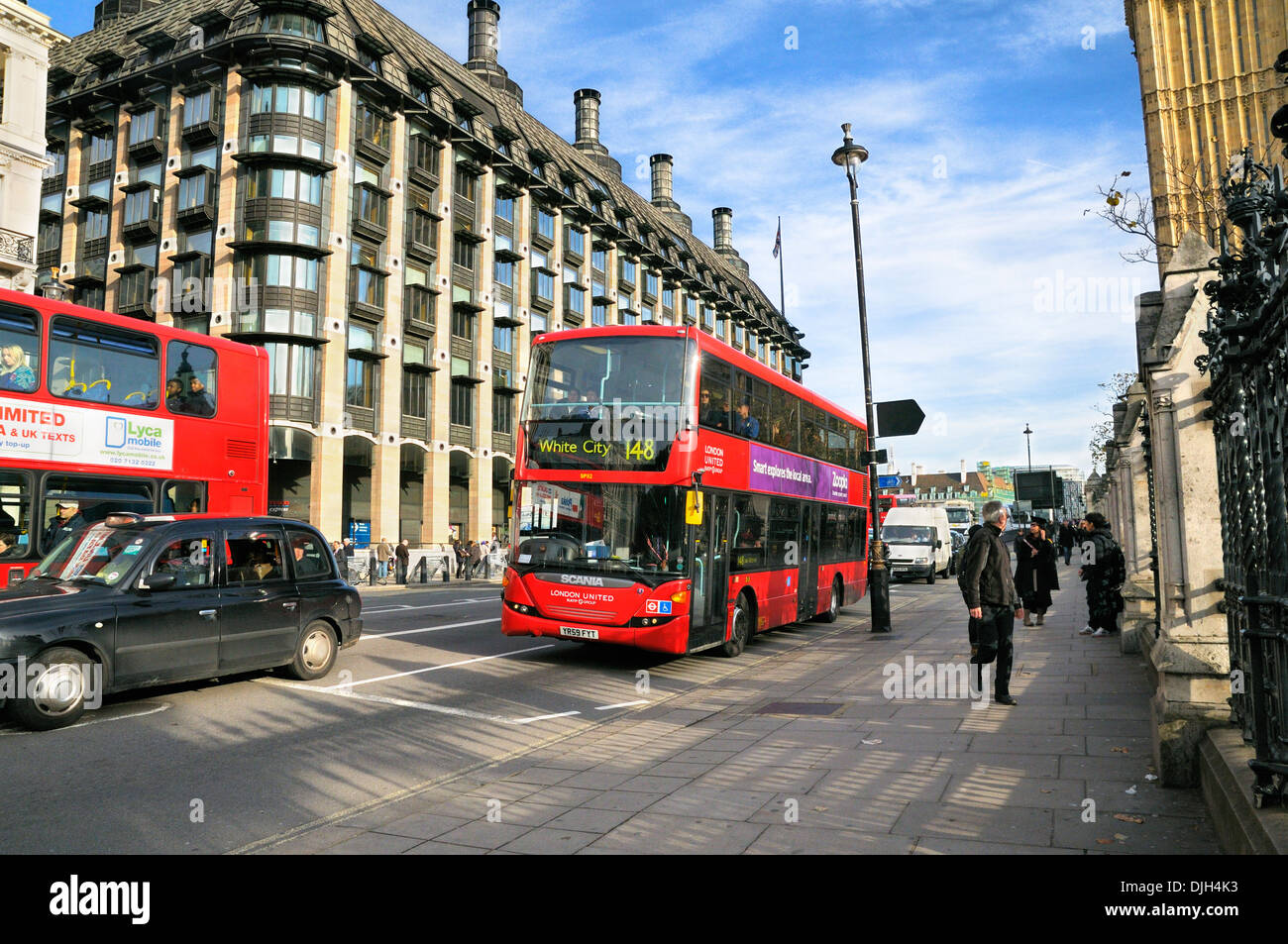 Autobús londinense pasando Portcullis House y la estación de metro de Westminster, de la ciudad de Westminster, Londres, Inglaterra, Reino Unido. Foto de stock