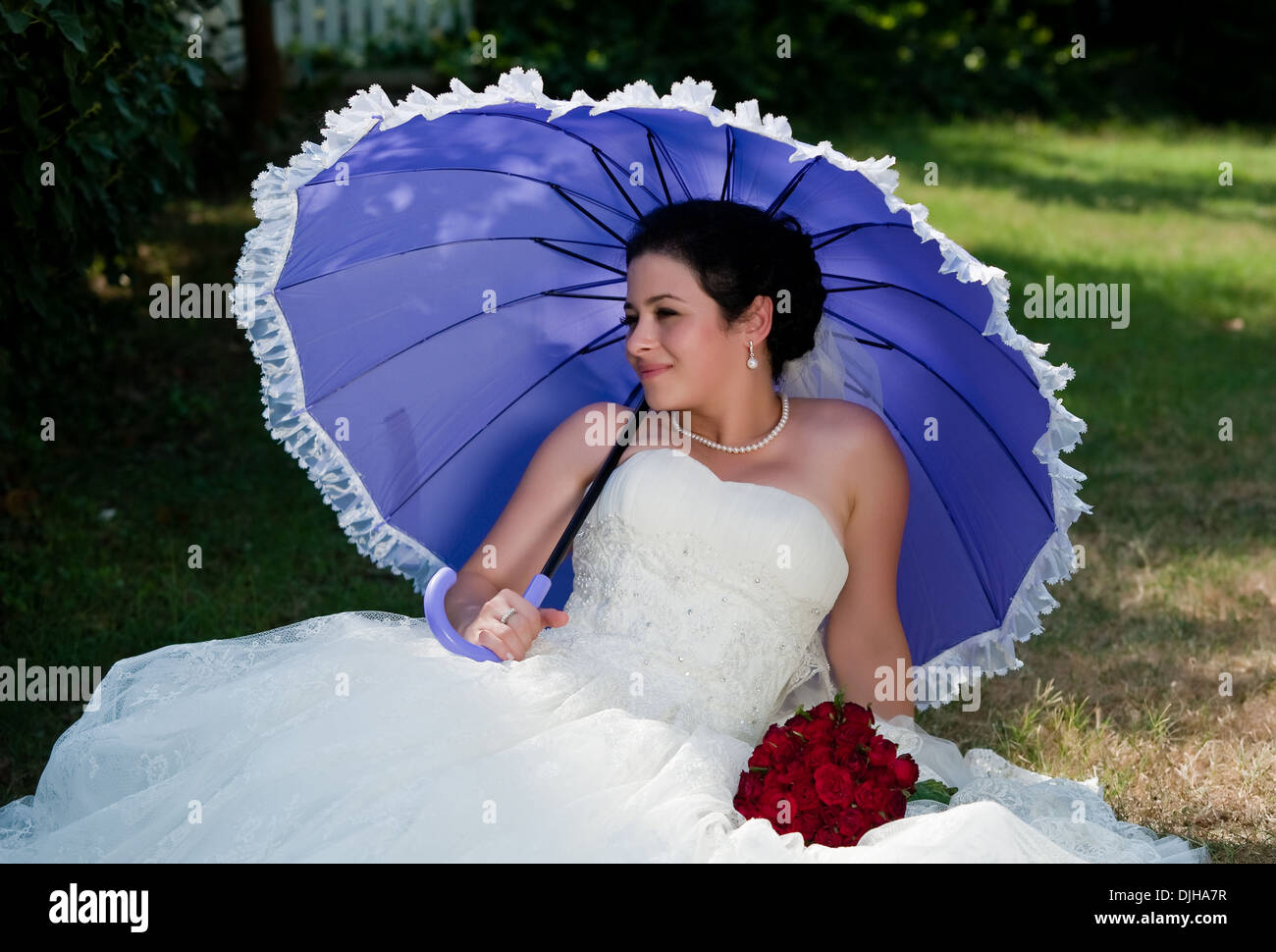 Novia sosteniendo paraguas y ramo de rosas rojas en la mano Fotografía de  stock - Alamy