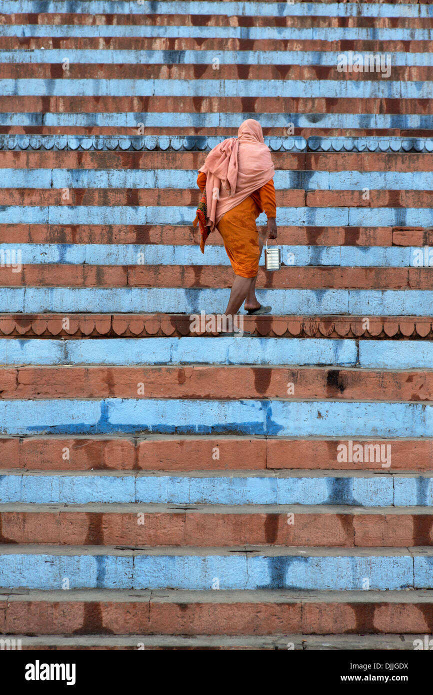 Un peregrino sube las escaleras del templo de Shiva en Varanasi. Foto de stock