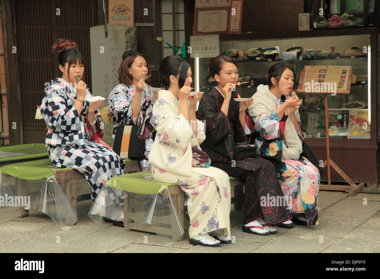 Japón, Kyoto, mujeres jóvenes en kimono de comer golosinas Foto de stock
