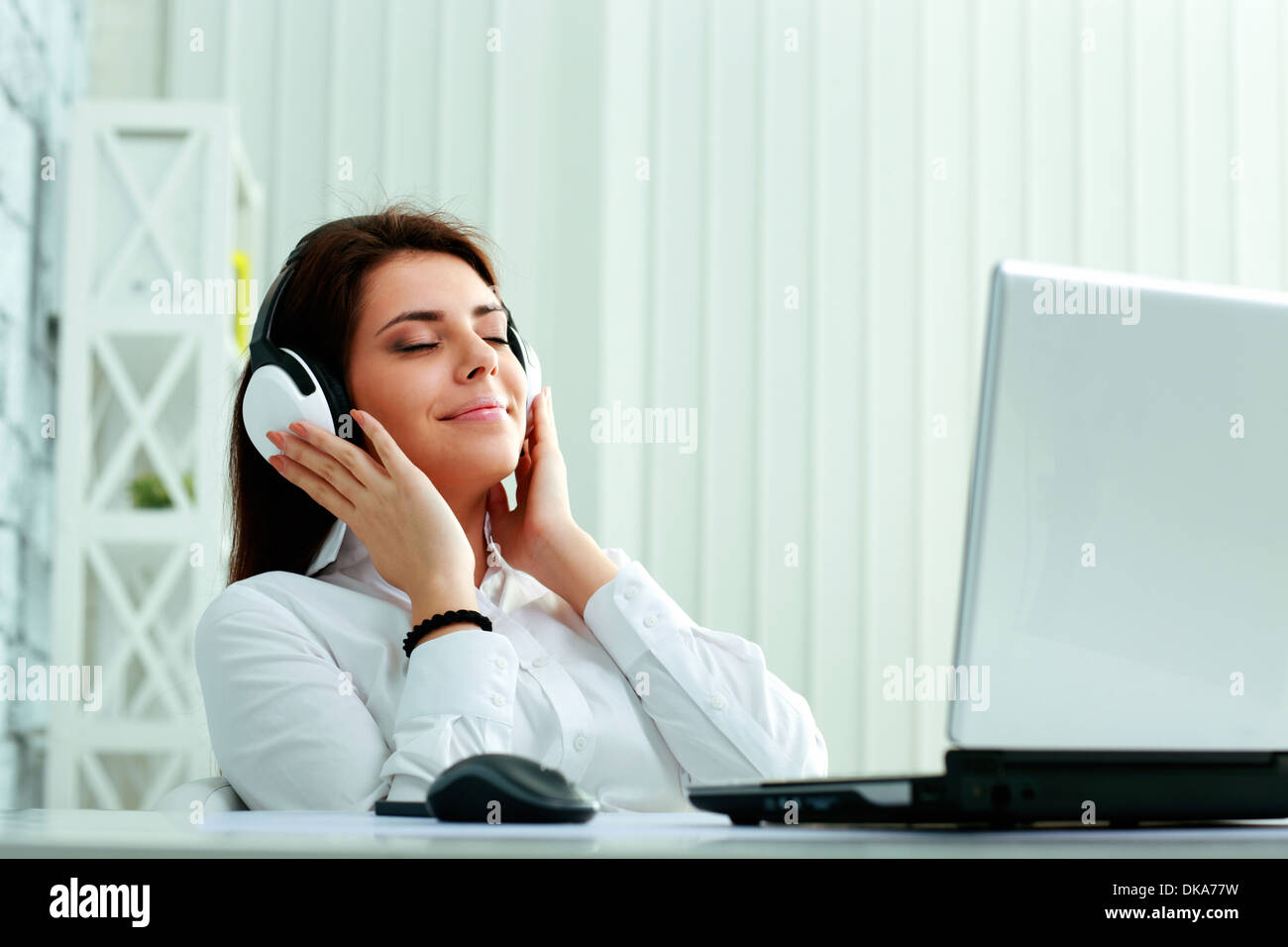 Hermosa joven empresaria escuchando música en auriculares Foto de stock