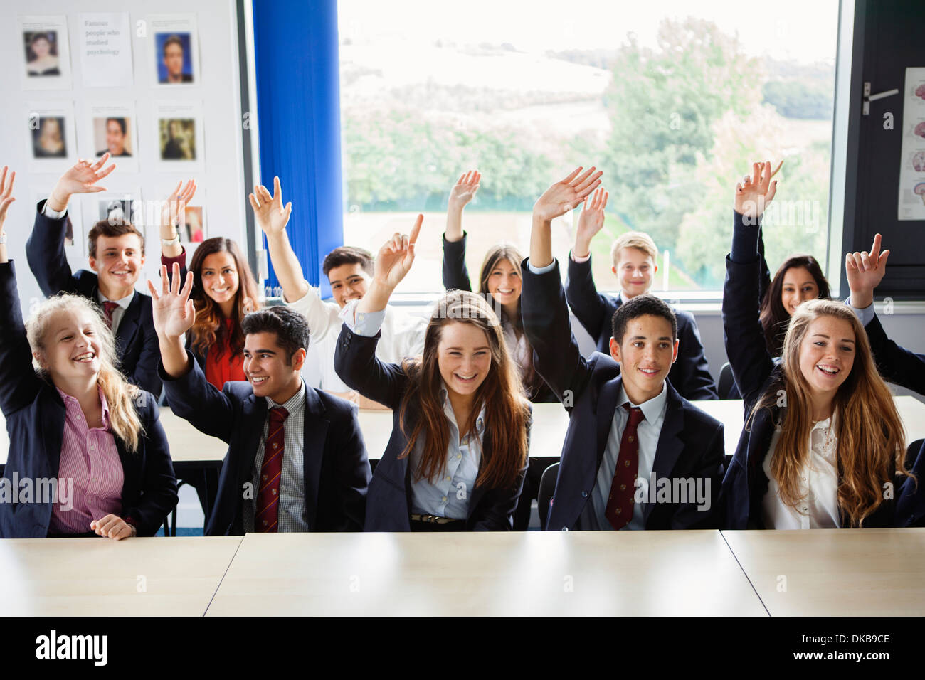 Los adolescentes escolares con manos levantadas en el aula Foto de stock