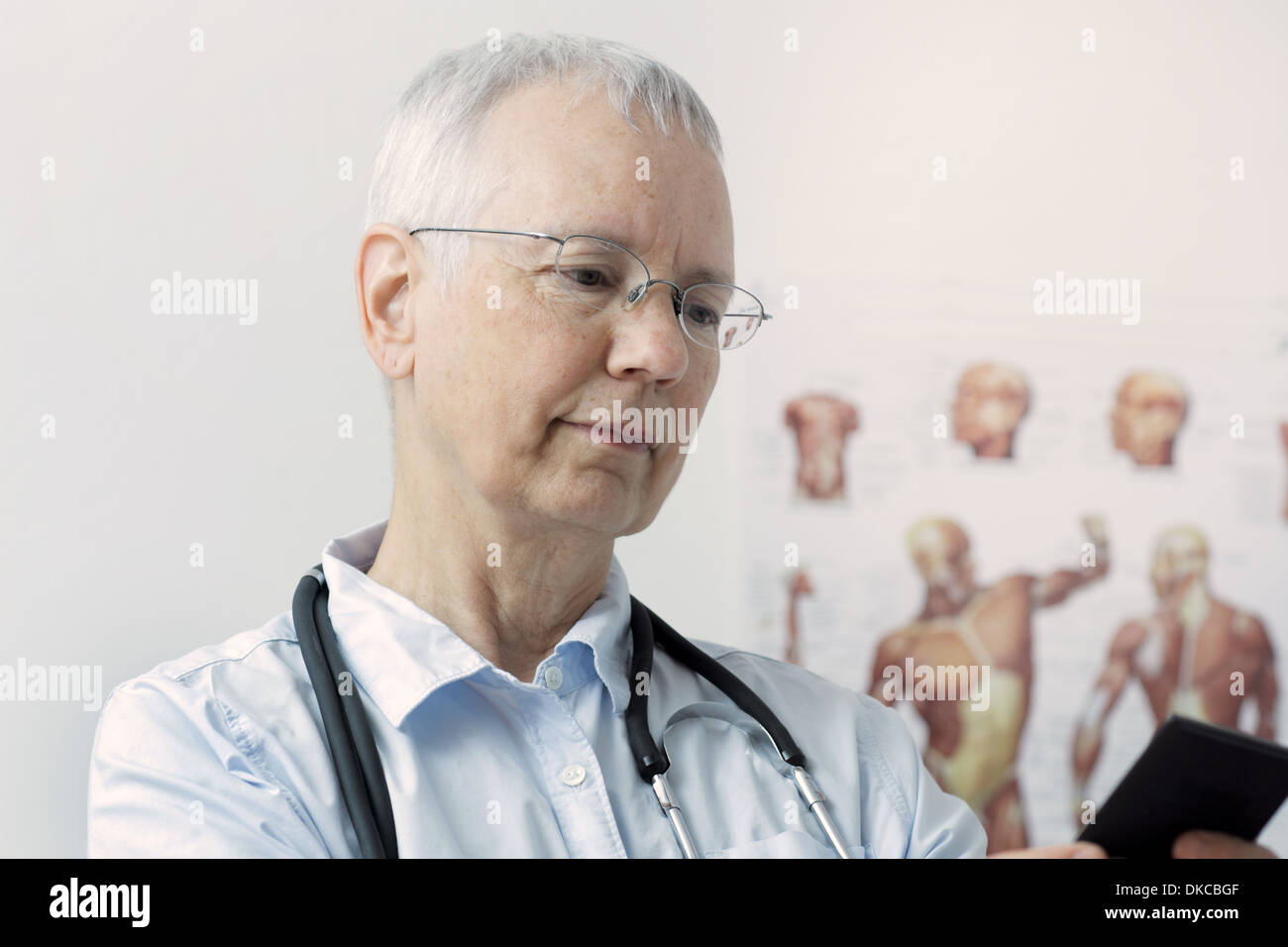 Una mujer reír doc con un músculo humano persona póster en el fondo y Foto de stock