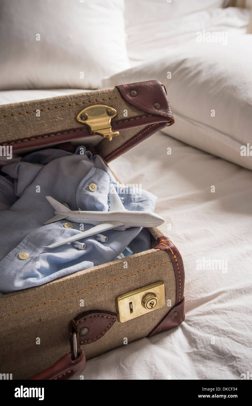 Maleta abierta sobre la cama con camisa y avión de juguete Fotografía de  stock - Alamy