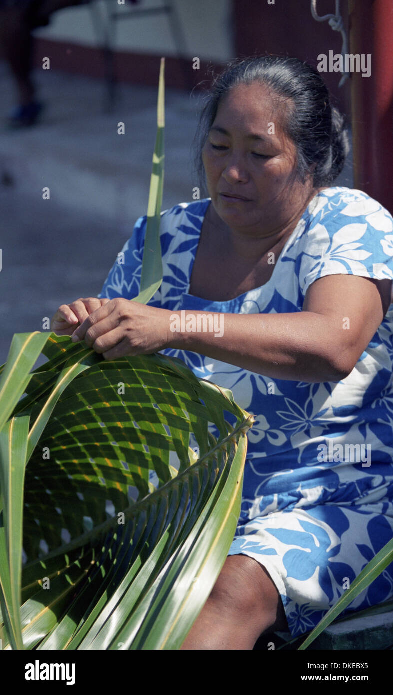 Una mujer Polinesia tejen canastos, empleando materiales de palma de coco. Foto de stock