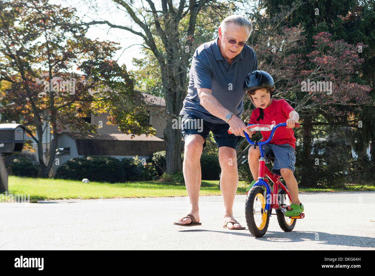 Abuelo animando joven a andar en bicicleta Foto de stock
