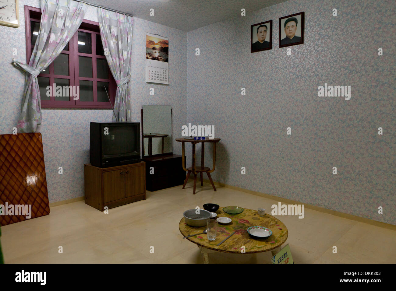 Maqueta del interior de la casa de la familia norcoreana que muestra retratos de Kim Il Sung y Kim Jong Il en la pared Foto de stock