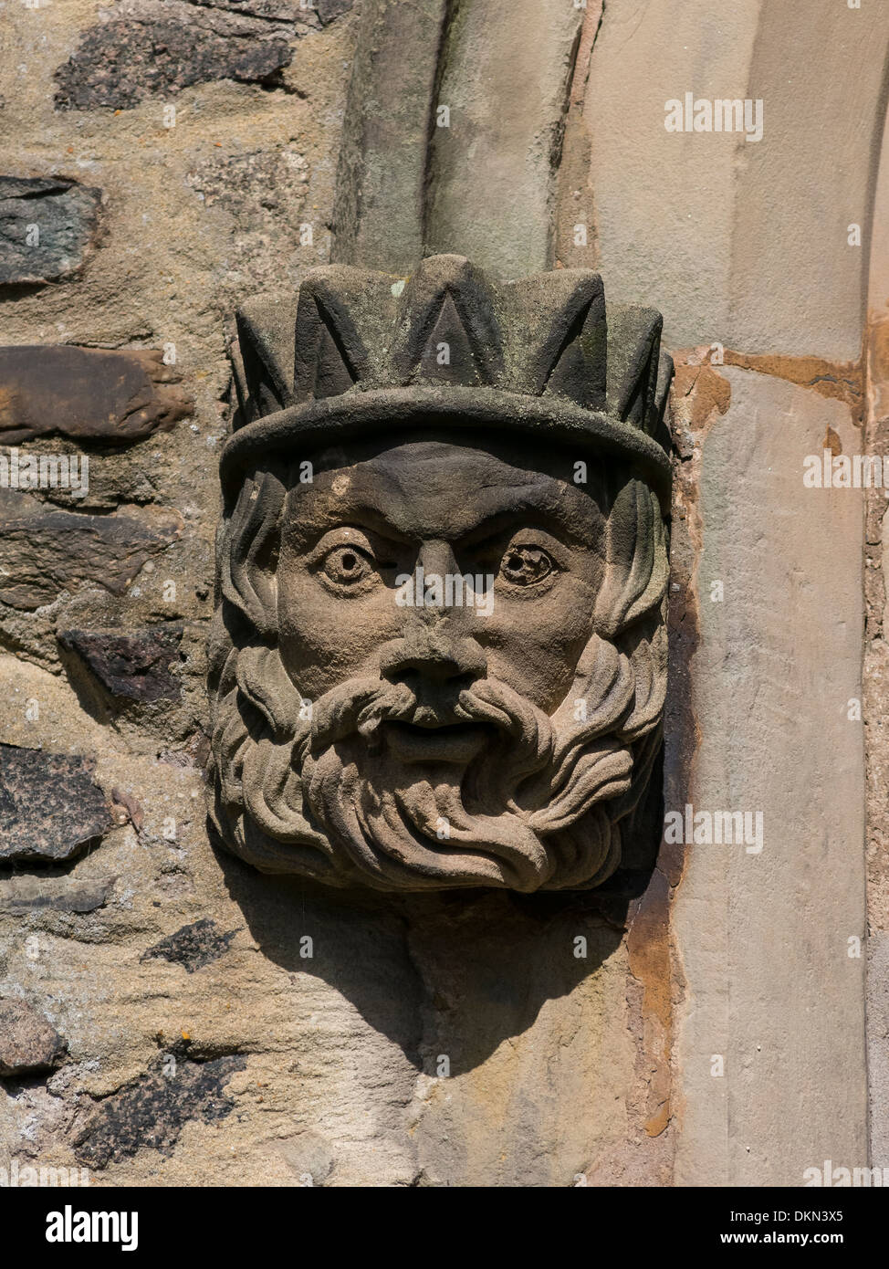 Pequeño muro de piedra tallada de boss barbudo Cabeza del rey con corona Foto de stock