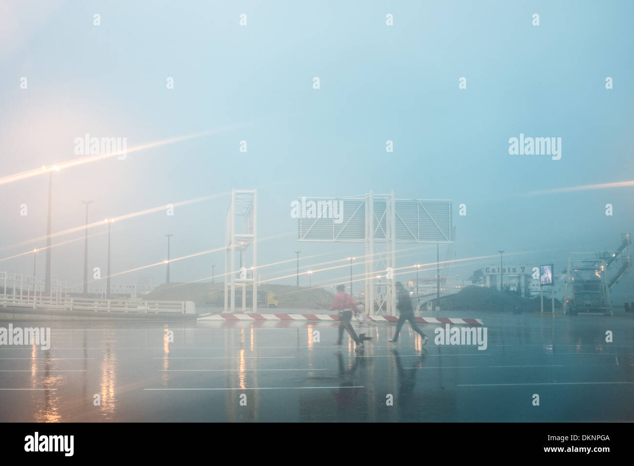 2 Personas correr bajo la lluvia, el puerto de Calais, Francia. Foto de stock