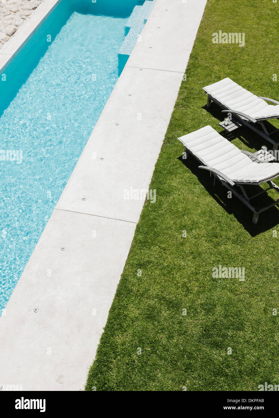 Reposeras en la hierba a lo largo de piscina Fotografía de stock - Alamy