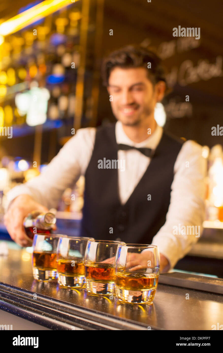 Bien vestida barman vertiendo en bourbon bar de lujo Foto de stock
