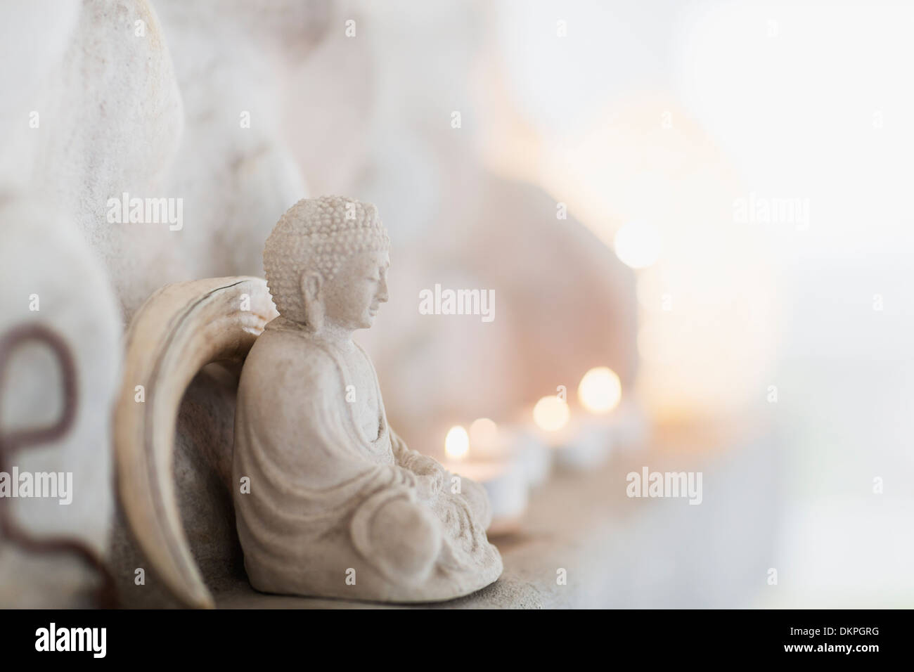 Figurilla de Buda y velas sobre cornisa Foto de stock