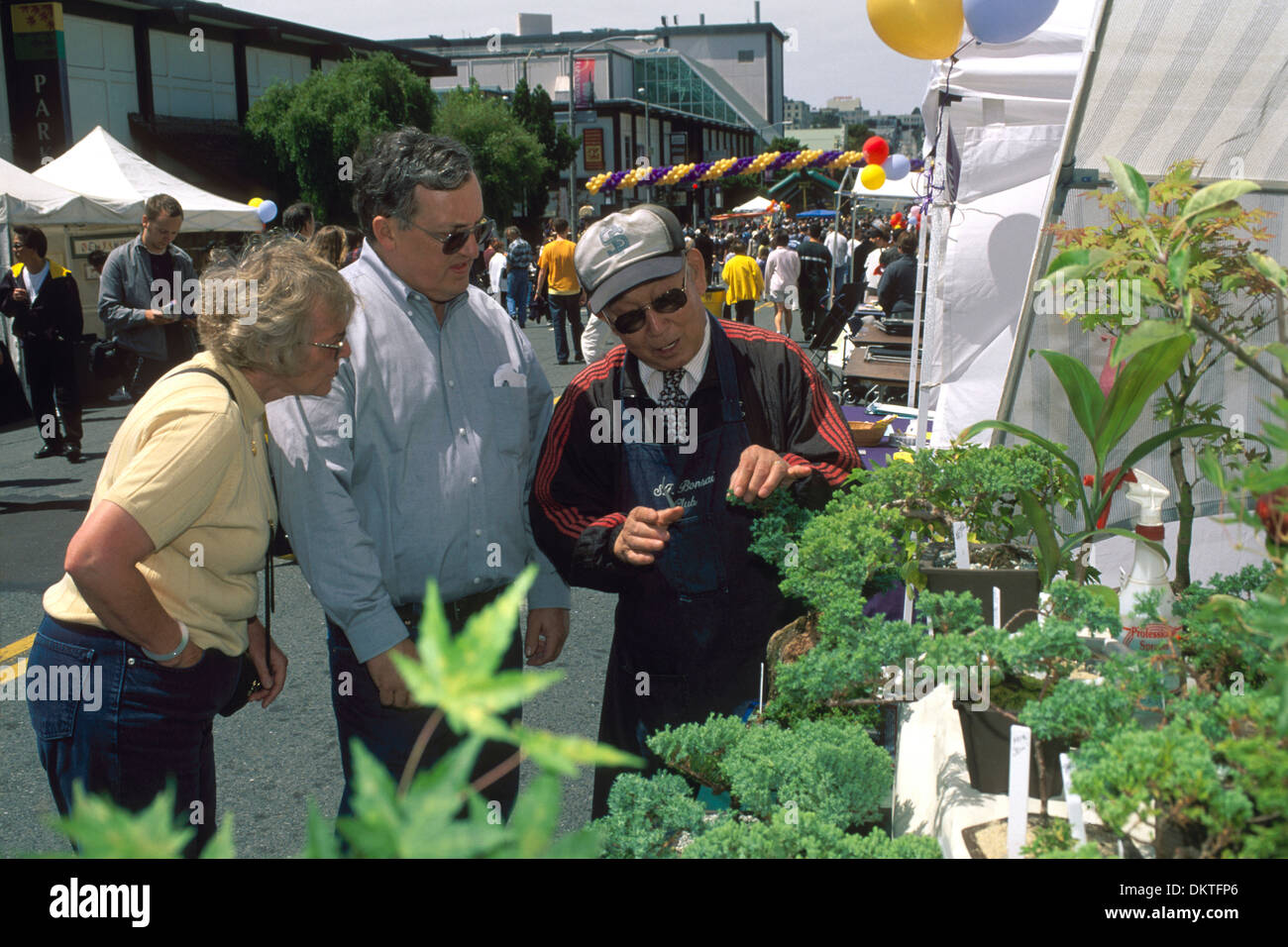 Bonsai vendedor callejero hablando con los clientes en la anual Feria