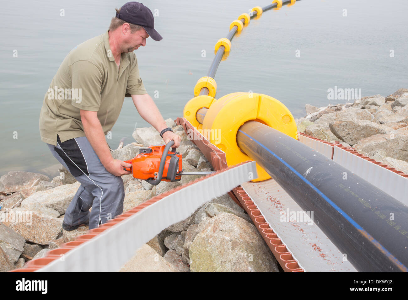 Trabajador en el trabajo con la sierra eléctrica Foto de stock