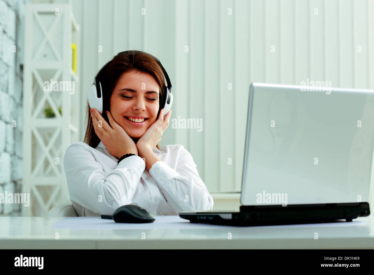 Hermosa joven empresaria escuchando música en auriculares con Office Foto de stock