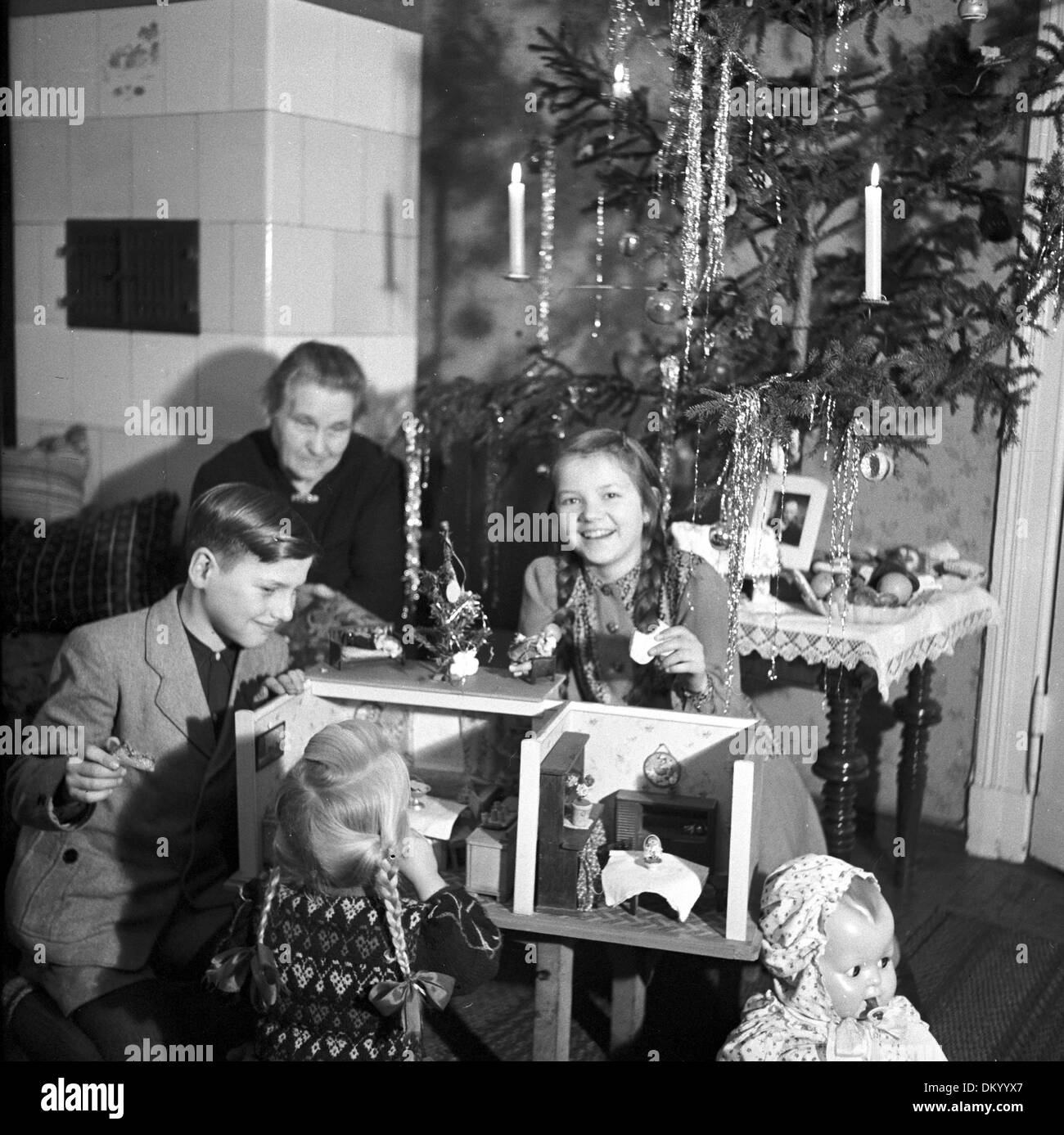 Una abuela relojes felizmente sus nietos, jugar con los regalos llegaron para Navidad en Berlín, Alemania, en 1949. Foto: Eva Richter Foto de stock