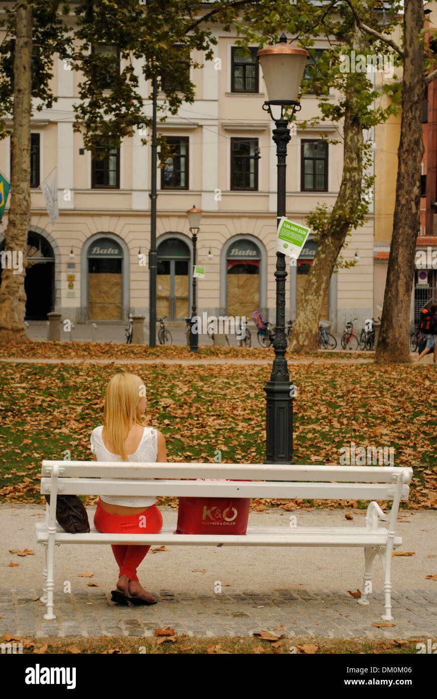 Chica sentada en un banco en un parque. Ljubljana, Eslovenia Foto de stock