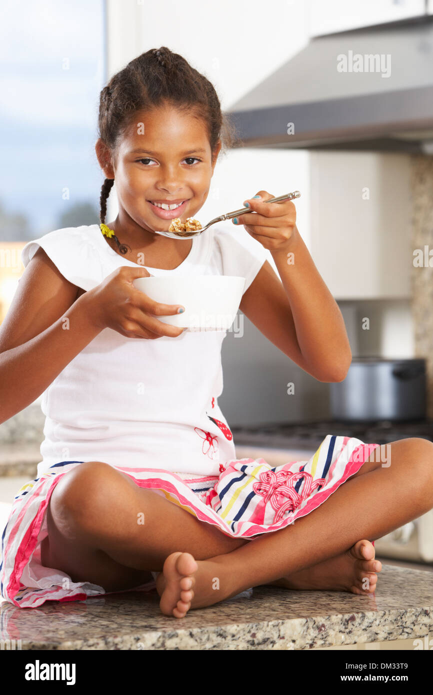 Chica en la cocina comiendo tazón de cereales para el desayuno Foto de stock